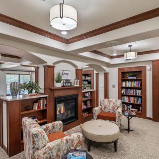 Cozy library interior with bookshelves, a fireplace, and comfortable seating.