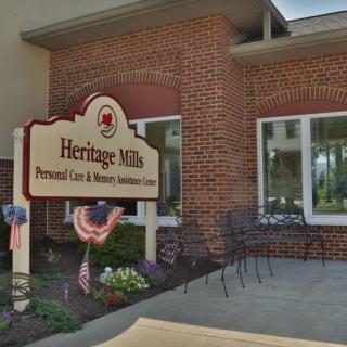 Entrance of Heritage Mills with a sign and outdoor seating area.