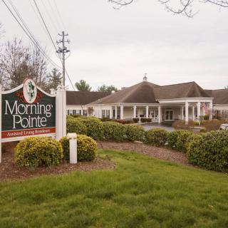 A view of an assisted living facility with a sign reading 'Morning Pointe' surrounded by well-maintained landscaping.