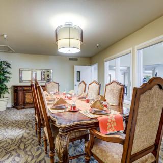An elegant dining room with a large wooden table and upholstered chairs, beautifully set for a meal.