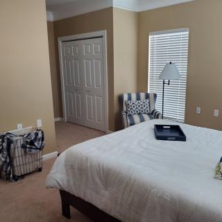 A neatly arranged bedroom with a bed, chair, and lamp.
