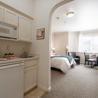 A cozy hotel room featuring a kitchenette and a comfortable sleeping area with a small dining setup.