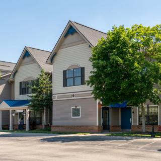 A commercial building with a tree in front, captured on a sunny day.