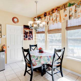 A cozy dining area with a table set for four, enhanced by natural light streaming through large windows and adorned with decorative elements.
