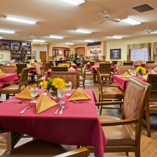 A well-arranged dining room with tables set and decorated with flowers and napkins.