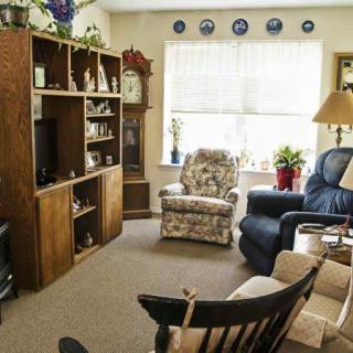 A cozy living room with armchairs, a bookshelf, and a television.