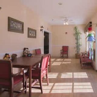 A sunlit dining area with red chairs and simple decor.