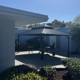 A sunny day in a landscaped backyard with a gazebo and patio.
