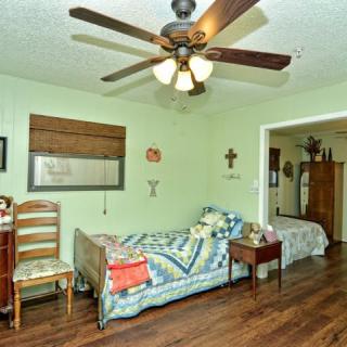 A cozy living room with a ceiling fan, sofa, and wooden flooring.