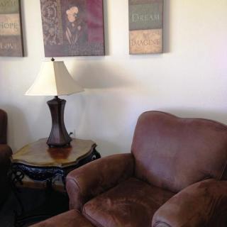 A cozy living room corner with a comfortable armchair, side table, and decorative wall art.