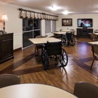 A dining area equipped with tables, wheelchairs, and a television for entertainment.