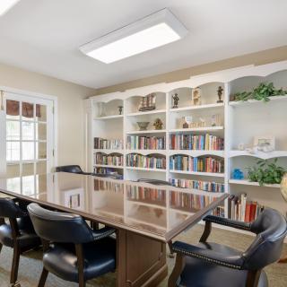 A well-organized conference room with a large table, chairs, and bookshelves filled with books.