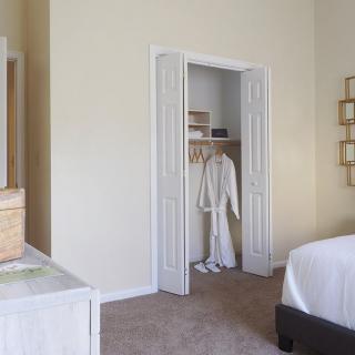 A minimalist bedroom with an open closet showing a robe hanging inside.