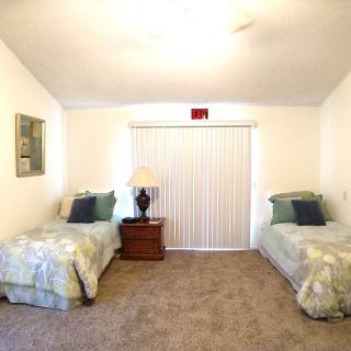A cozy bedroom with twin beds and a central nightstand under soft lighting.