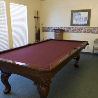 A billiards table with a maroon felt surface in a well-lit game room.