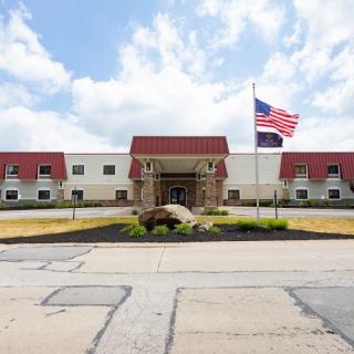 A building with a red and white facade, featuring an entrance with a flagpole displaying the American flag under a cloudy sky.