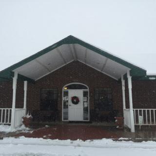 A brick building with a covered porch and snowy surroundings.