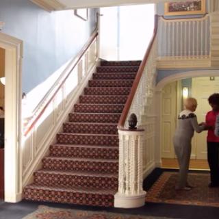 A welcoming interior showcasing a beautifully carpeted staircase, where two individuals engage in conversation.