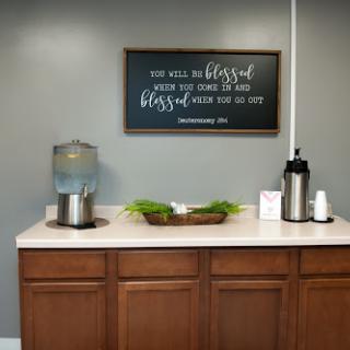 A welcoming office space featuring a water cooler, decorative elements, and an inspirational sign.
