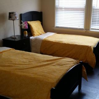 A cozy bedroom featuring twin beds with yellow bedding and a lamp on the bedside table.