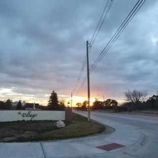 A serene sunset illuminating the horizon amidst a cloudy sky.