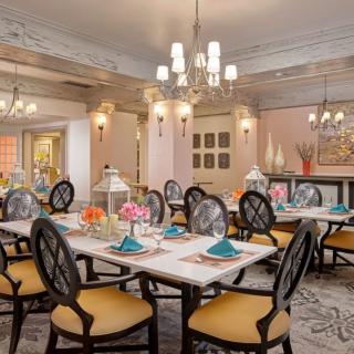 An elegantly decorated dining room featuring chandeliers and beautifully set tables.
