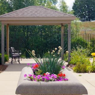 A serene garden area featuring a canopy, vibrant flowers, and a comfortable bench for relaxation.