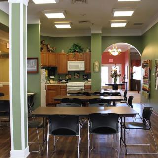 A cozy kitchen and dining area with tables and chairs, featuring a warm color scheme and an archway.
