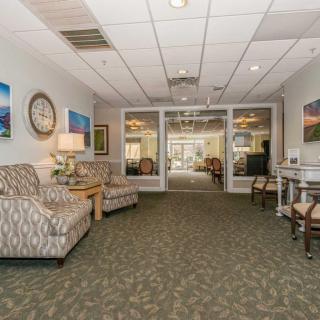 A cozy waiting area with armchairs and artwork on the walls, featuring a carpeted floor and soft lighting.