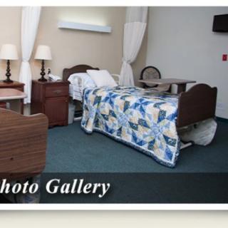 A hospital room with a bed, nightstand, and lamp.