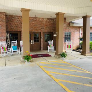 Entrance of a building with rocking chairs and plants under a covered walkway.
