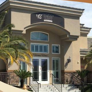 A commercial building entrance featuring palm trees and a modern architectural design.