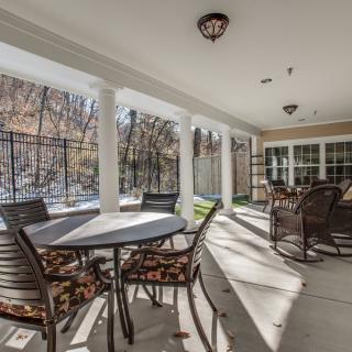 A covered patio with various tables and chairs, providing a cozy outdoor seating area bathed in sunlight.