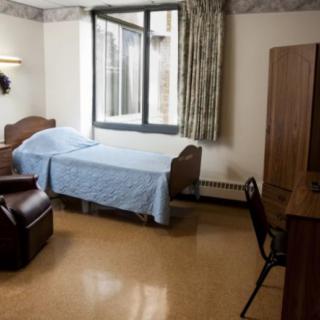 A tidy hospital room with a bed, chair, and window.