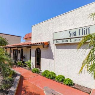 Exterior view of a restaurant with signage and palm trees on a sunny day.