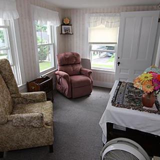 A cozy living room with multiple chairs and large windows letting in natural light.
