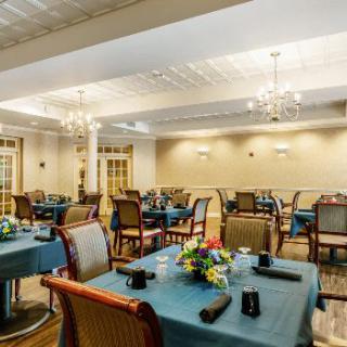 Elegant dining area with neatly arranged tables and chairs, adorned with chandeliers and floral centerpieces.