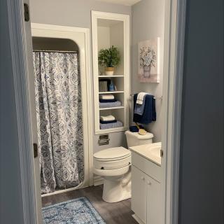A neatly organized bathroom with a shower curtain, towels, and decorative elements.