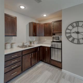 A modern kitchen with dark wood cabinets and a wall clock.