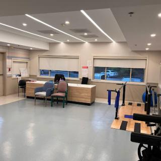 A modern healthcare waiting area featuring a reception desk and rehabilitation equipment.
