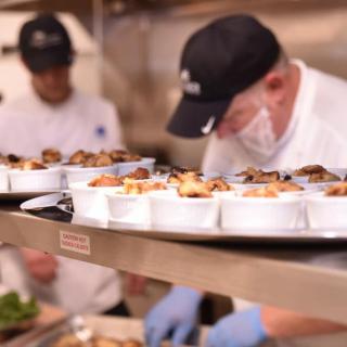 Chefs preparing dishes in a busy restaurant kitchen.