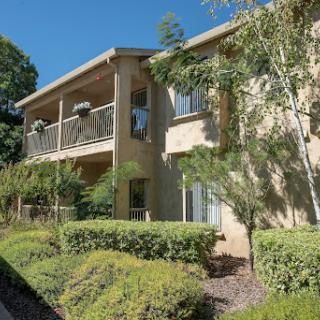 A well-maintained apartment building featuring balconies and lush landscaping.