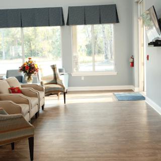 A cozy living room with natural light, featuring comfortable seating and a wall-mounted TV.