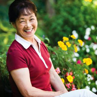 A joyful woman enjoying a sunny day among vibrant flowers.