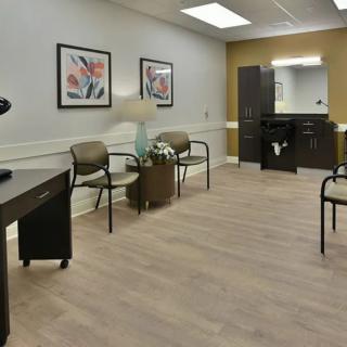A modern waiting room with chairs, artwork on the walls, and a reception area.