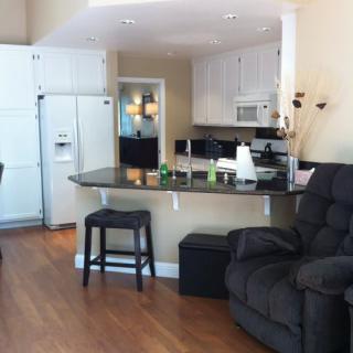 A cozy open-concept kitchen and living area featuring a recliner and bar stools at a counter.