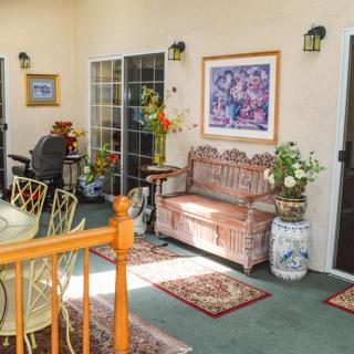 A cozy outdoor patio area with a decorative bench, plants, and artwork.