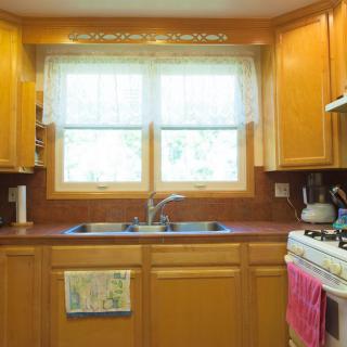 A cozy kitchen with wooden cabinets and a large window above the sink.