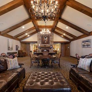 A luxurious and cozy living room with wood beams and chandeliers.
