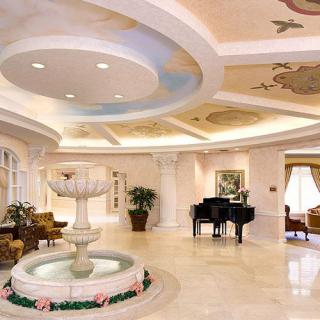 A luxurious hotel lobby featuring a grand piano, fountain, and elegant seating area with marble flooring.